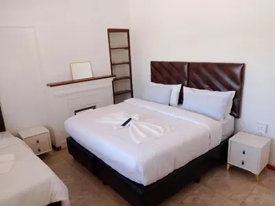 a bedroom with a large white bed with a cross on it at Duminy Guest Lodge in Bellville