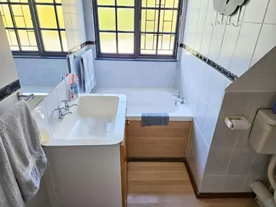 a bathroom with a sink and a bathtub and a sink and a window at Indoor Pool Paradise in Stellies in Stellenbosch