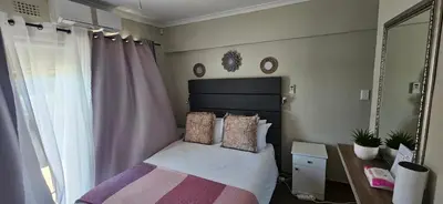 a small bedroom with a bed and a mirror at Vues Du Mont in Hermanus