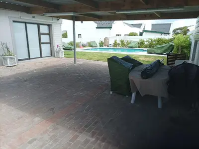 a patio with a table and chairs and a pool at Vues Du Mont in Hermanus