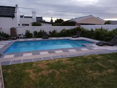 a small swimming pool with two chairs in a yard at Vues Du Mont in Hermanus