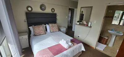 a bedroom with a large bed and a sink at Vues Du Mont in Hermanus