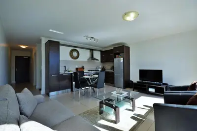 a living room with a couch and a table at Quayside 1 Bedroom Apartment in Century City in Cape Town