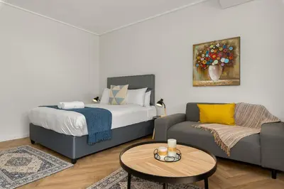 a bedroom with a bed and a couch and a table at On Park Apartments in Cape Town