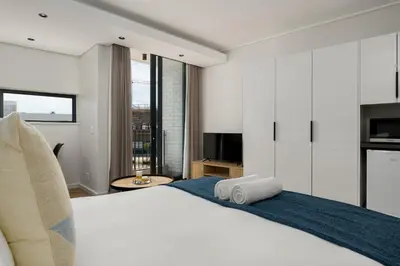 a bedroom with a large white bed and a television at On Park Apartments in Cape Town