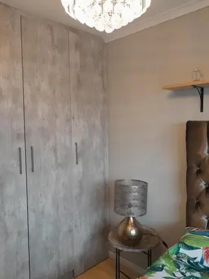 a bedroom with a bed and a cabinet and a lamp at Yannas Guesthouse in Cape Town