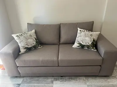 a couch with two pillows on it in a room at Te Môi in Paarl