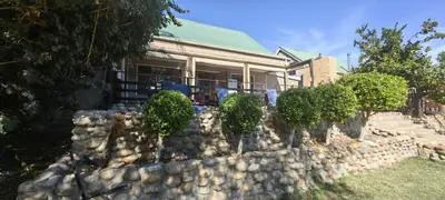 a stone wall in front of a house at Franschoek - Holiday House on the River in Hou Moed