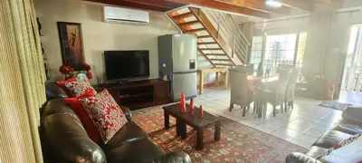 a living room with a couch and a television and a table at Franschoek - Holiday House on the River in Hou Moed