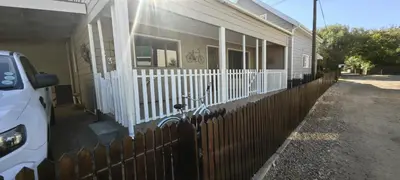 a fence in front of a house with a porch at Franschoek - Holiday House on the River in Hou Moed