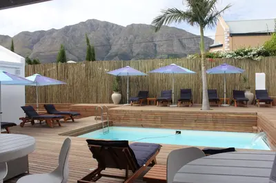 a pool with chairs and umbrellas on a deck at theLAB Franschhoek in Franschhoek