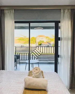 a bedroom with a bed and a view of a balcony at Goodness Century Apartment in Cape Town