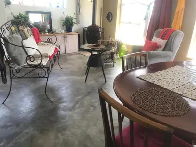 a living room with a table and chairs and a wood stove at 120 steps to the beach in Pringle Bay