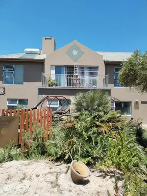 a house with a balcony and a yard with plants at 120 steps to the beach in Pringle Bay