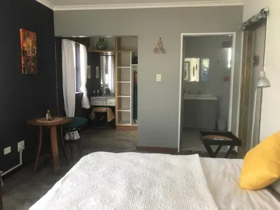 a bedroom with a bed and a table and a bathroom at 120 steps to the beach in Pringle Bay