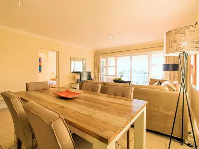 a living room with a wooden table and a couch at Goldwater 7 in Gordonʼs Bay