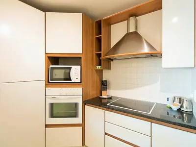 a kitchen with white cabinets and a stove top oven at Goldwater 7 in Gordonʼs Bay