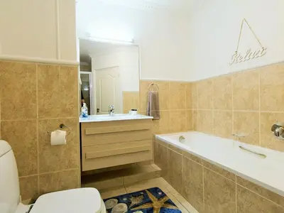 a bathroom with a tub and a toilet and a sink at Goldwater 7 in Gordonʼs Bay