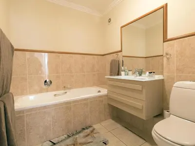 a bathroom with a tub and a toilet and a sink at Goldwater 7 in Gordonʼs Bay