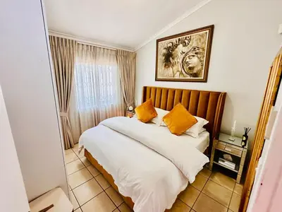 a bedroom with a bed with white sheets and orange pillows at Dolce in Cape Town