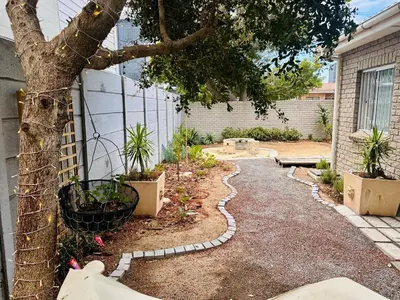 a garden with a tree next to a house at Dolce in Cape Town