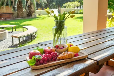 a plate of fruit on a wooden table with a vase at Farmhouse in Cape Town