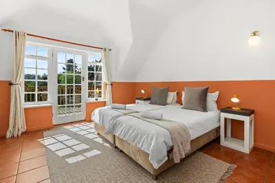 a bedroom with a large bed with orange walls at Farmhouse in Cape Town
