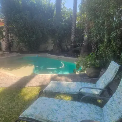 a swimming pool with two chairs and a bench in front at Mimi's in Plattekloof