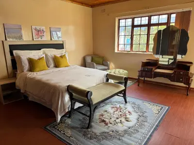a bedroom with a bed and a chair and a television at Miches House in Cape Town