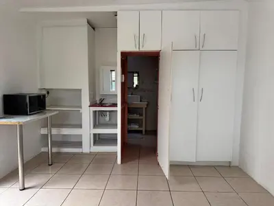 a kitchen with white cabinets and a tiled floor at Miches House in Cape Town