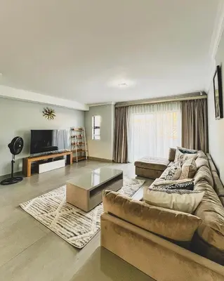 a living room with a couch and a tv at Hope Century Apartments in Cape Town