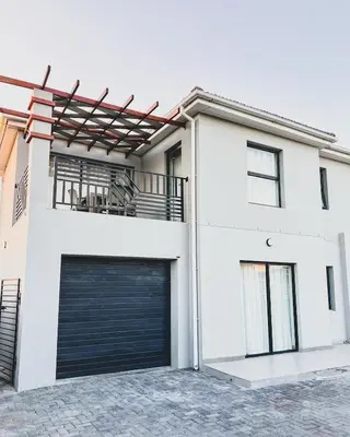 a white house with a black garage door at Hope Century Apartments in Cape Town