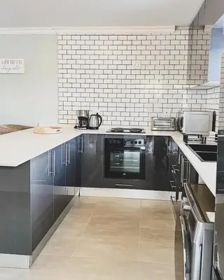 a kitchen with black cabinets and a black oven at Hope Century Apartments in Cape Town
