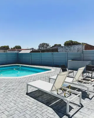a patio with two chairs and a swimming pool at Hope Century Apartments in Cape Town