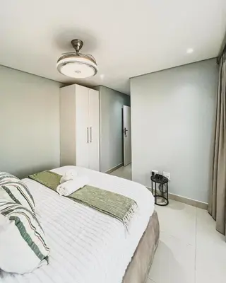 a bedroom with a large bed with white sheets at Hope Century Apartments in Cape Town