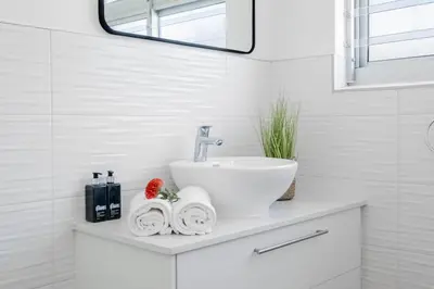 a white bathroom with a sink and a mirror at Self-Catering Winelands Views Apartment Stellenbosch in Stellenbosch