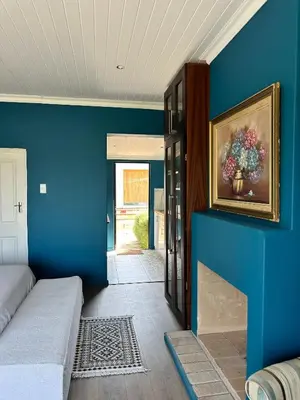 a room with a blue wall with a painting of flowers at Blue Cottage, Elgin Grabouw in Grabouw