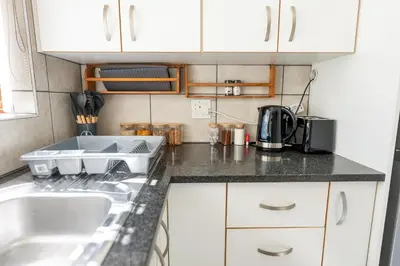 a kitchen with white cabinets and a sink at Mystical Serenity in Durbanville