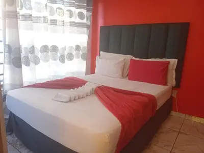 a bedroom with a large bed with red and white pillows at Neo & Ruks rooms parow 2 in Avondale