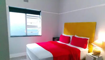 a bedroom with a red and white bed with a window at Neo & Ruks rooms parow 2 in Avondale