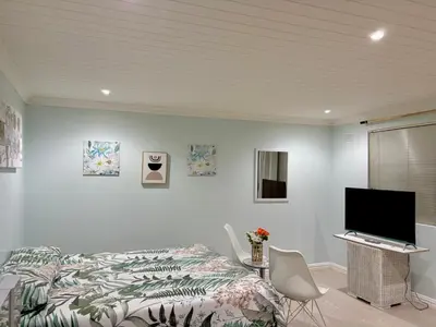 a bedroom with a bed and a flat screen tv at Bachelor Flat A in Goodwood