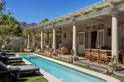 a backyard with a swimming pool and a house at Pink Door Franschhoek by The Oyster Collection in Franschhoek