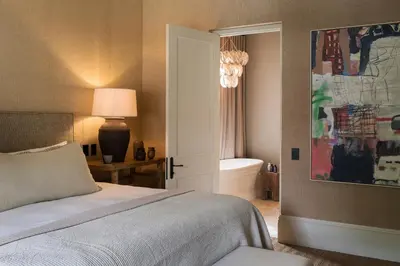 a bedroom with a bed and a bathroom with a tub at Pink Door Franschhoek by The Oyster Collection in Franschhoek