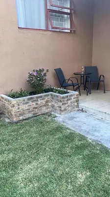 a brick planter with chairs and a table in a patio at Bergstreet in Hermanus
