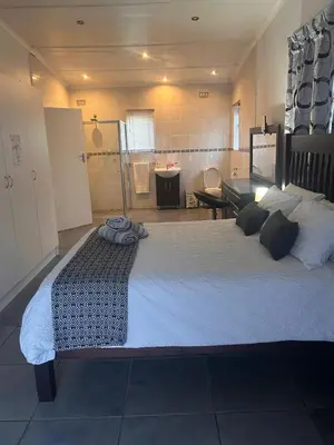 a large bed in a room with a bathroom at Bergstreet in Hermanus