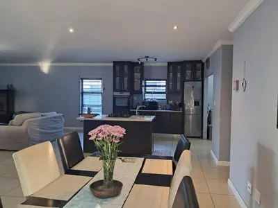 a kitchen and living room with a table with flowers on it at Spacious Home-Quiet area, Kuils river, Cape Town in Blackheath