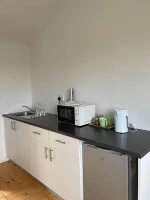 a kitchen with a black counter top with a microwave at Green Cottage, Elgin Grabouw in Grabouw