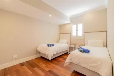 two beds in a room with white walls and wooden floors at Somer Sout in Voelklip, Hermanus in Hermanus