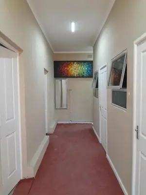a hallway with a red floor and a painting on the wall at BDC Paarl Accommodation and Guest House in Paarl