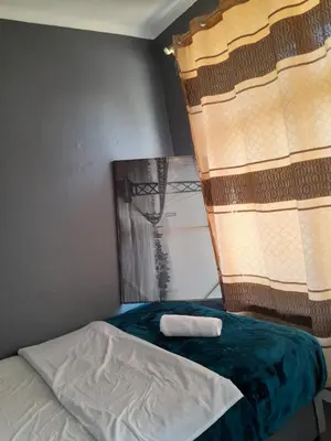 a bedroom with a bed with a blue blanket and a window at BDC Paarl Accommodation and Guest House in Paarl